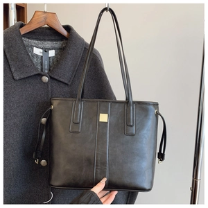 Detail of black matte leather tote bag with gold hardware and side drawstrings