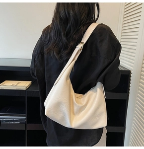 Detailed view of cream white leather shoulder bag with minimalist stitching and adjustable strap