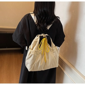 Detail of off-white canvas tote with bright yellow drawstring and black shoulder strap