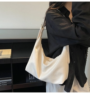 Modern off-white leather tote bag styled on model in a minimalist setting