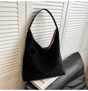 Close-up of black matte suede tote bag on a leather sofa with minimalist background