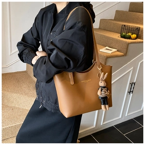 Détail du sac cabas en cuir marron avec texte doré et pendentif lapin mignon