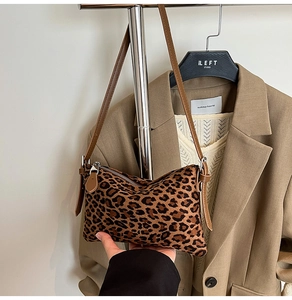 Detailed close-up of leopard print shoulder bag with brown leather strap and silver zipper