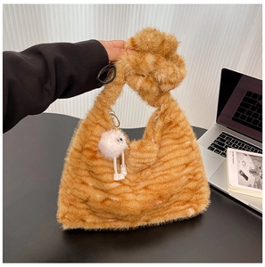 Detail of plush orange striped shoulder bag with a unique knot handle and monster charm