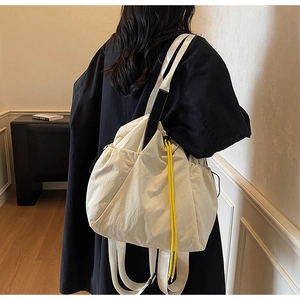 Detail view of a beige nylon tote bag with contrasting yellow drawstrings and soft texture