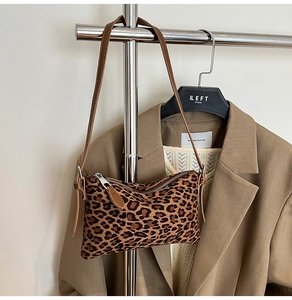 Detail of leopard print underarm bag with brown leather strap on a stylish hanger
