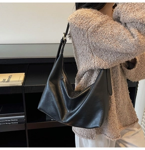 Detail of black leather hobo bag featuring adjustable metal buckle and fashion trend logo