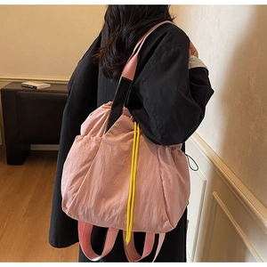 Detail view of pink nylon tote bag showing contrast drawstrings and woven strap textures