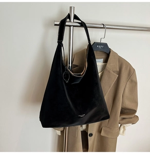 Detailed macro view of black suede tote bag with contrast white stitching and wide strap