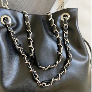 Detail of premium silver chain interwoven with black leather strap on a bucket bag