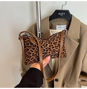 Detailed macro shot of leopard print shoulder bag with brown leather strap and silver zipper