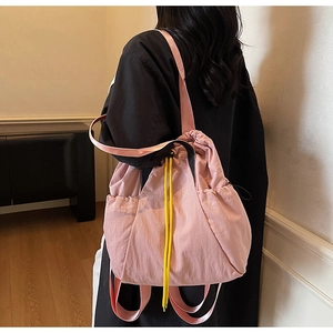Detailed side view of pink drawstring nylon tote bag with yellow contrast straps and pocket