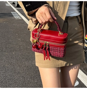 Detail of burgundy leather and tweed square handbag with cherry charm and gold zippers