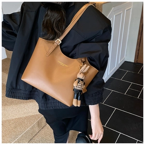 Brown leather tote bag featuring a gold fashion logo and a houndstooth rabbit charm detail