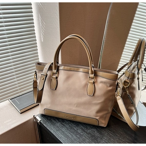 Détail du sac fourre-tout en nylon camel avec bordure en cuir marron et logo doré