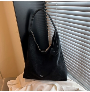Detail of a black matte hobo bag showing its textured surface and brand lettering