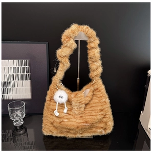 Detailed texture of brown plush shoulder bag with fluffy monster charm and ruched strap