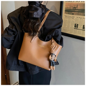 Détail du sac cabas en cuir marron avec breloque lapin mignonne et logo de mode