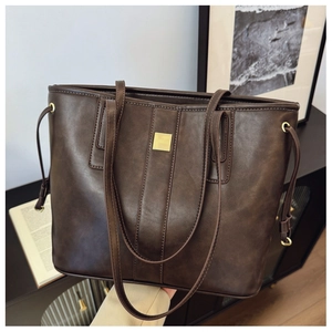 Detail of large dark brown leather tote bag with square gold buckle and handles