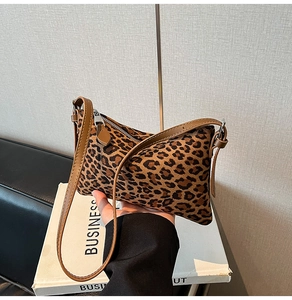 Detailed close-up of leopard print shoulder bag with brown strap and zip closure