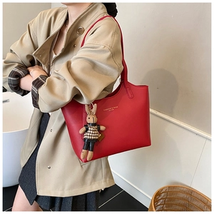 Détail du sac cabas en cuir rouge avec lettrage doré et charmant lapin en peluche