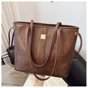 Detail of dark brown tote bag with leather texture and square golden hardware accent