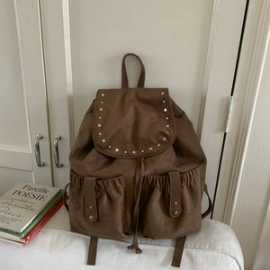 Detail of dark brown matte canvas backpack with silver rivets and dual drawstring pockets