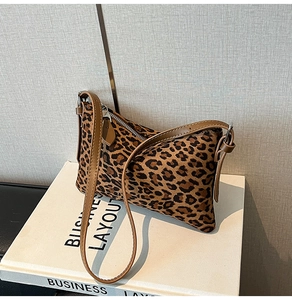 Detail view of the brown leopard print faux fur texture and brown leather strap on bag