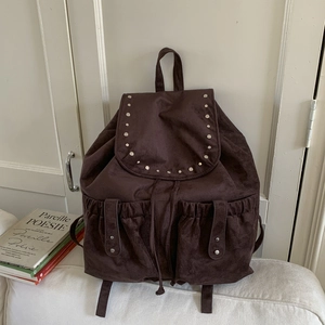 Detail of dark brown canvas backpack with silver rivets and drawstring closure