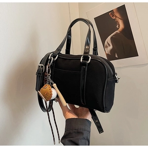 Detail of Boston canvas handbag featuring glossy patent trim and baseball themed charm