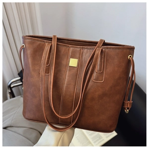 Detail of deep brown faux leather tote bag with vintage texture and gold square buckle