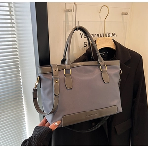 Détails d'un sac cabas en nylon avec anses en cuir et garnitures métalliques gravées