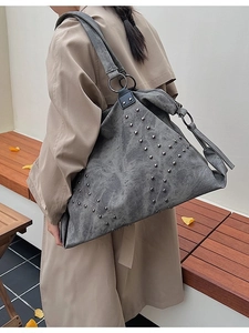 Gray large capacity tote bag with silver rivets and wide strap shown on a model
