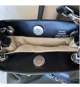 Detail of strong magnetic buckle on black pebble leather bucket bag for easy opening