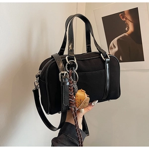 Detail of Boston canvas bag with black leather straps and decorative charm accessory