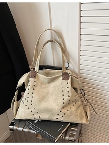 Chic large capacity tote bag in sage green suede with rivet detail on a suitcase