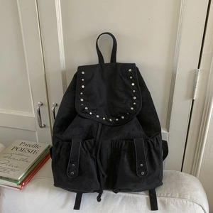 Detailed view of black vintage canvas backpack featuring silver rivets and drawstring closure
