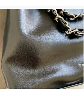 Macro view of black lychee leather texture and silver chain strap on fashion bucket bag