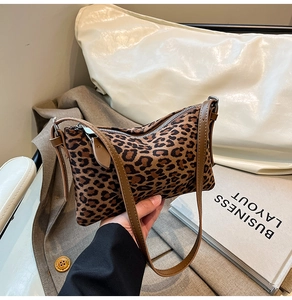 Close-up of leopard print baguette bag with brown strap and silver zipper closure
