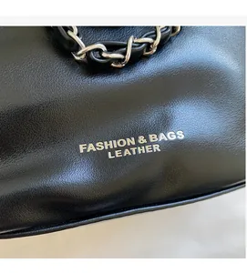 Close-up of black leather bucket bag with silver lettering and leather-intertwined chain strap