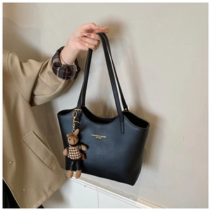 Détail du cabas en cuir noir avec logo doré et pendentif ours mignon attaché