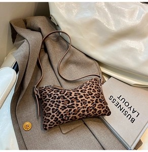Detail of leopard print crossbody bag with metal zipper on a textured brown blazer