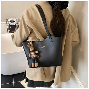 Détail d'un cabas en cuir noir avec logo doré et pendentif de lapin marron pelucheux