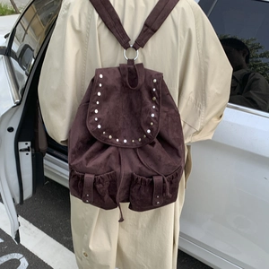 Detail of vintage coffee canvas backpack with metal studs on model wearing beige coat