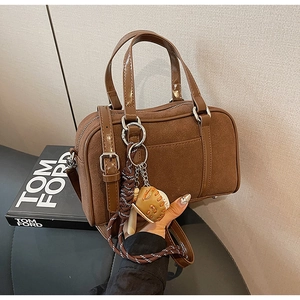 Brown suede Boston bag detail with unique baseball glove and wooden bat charm accessory
