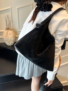 Minimalist large black suede tote bag with white logo worn by model on shoulder
