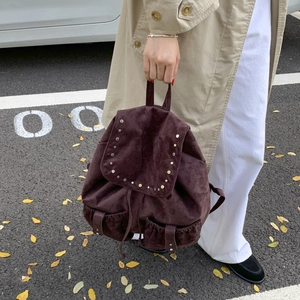 Detail of dark brown canvas backpack with silver stud rivets and buckle pockets