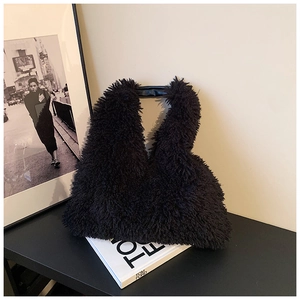 Close-up of black fuzzy faux fur tote bag with stylish leather handles and soft texture