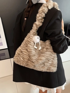 Faux fur shoulder bag with tiger stripes and plush charm shown on model's shoulder