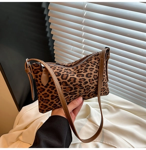 Detail of leopard print underarm bag featuring premium brown leather strap and metal zipper
